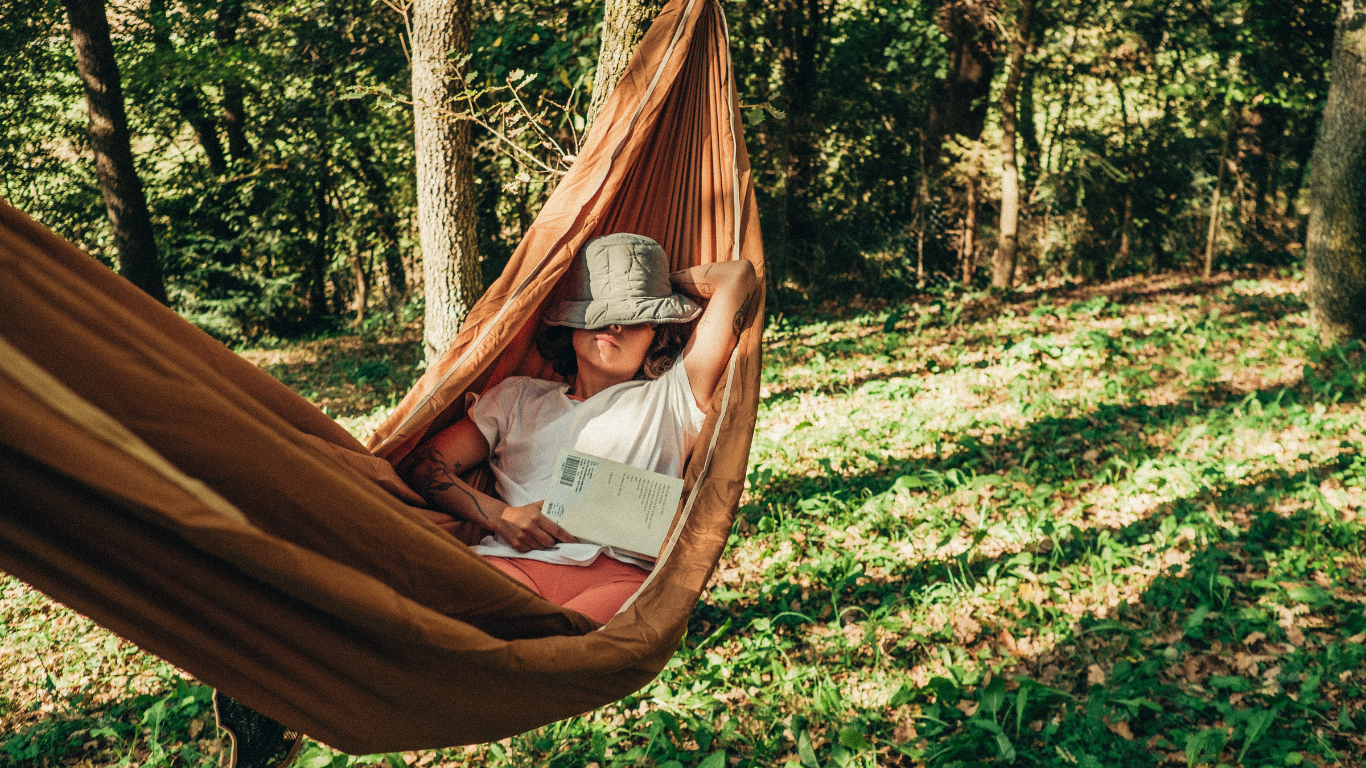 Woman sleeping in a hammock with a book in her hand