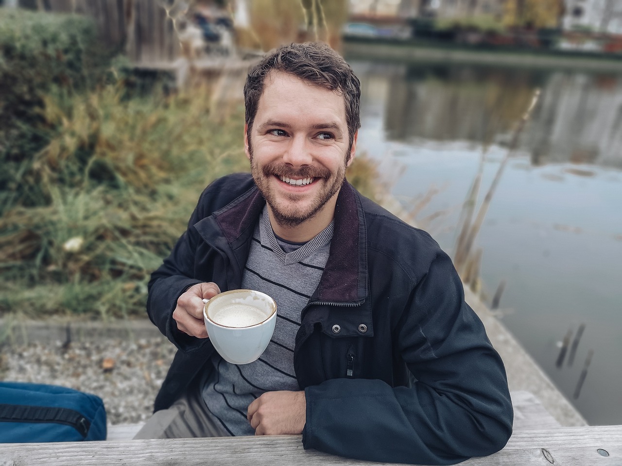 Man drinking coffee by a river